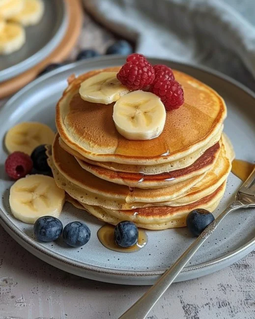 Stack of easy fluffy pancakes on a plate with syrup and berries