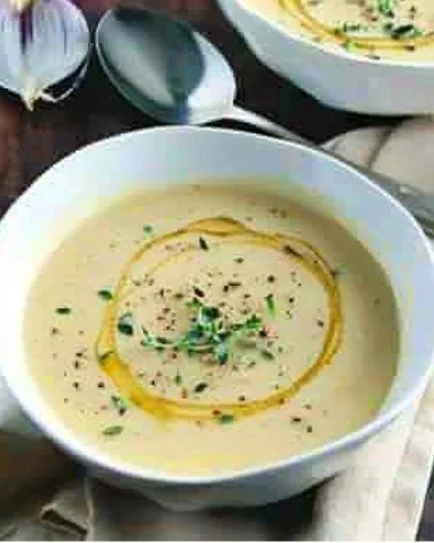 Delicious bowl of homemade Potato Leek Soup garnished with herbs.