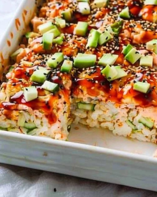 Baked sushi dish with layers of rice, seafood, and toppings in a casserole dish