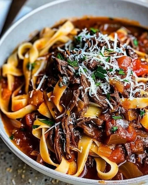 Sunday Slow Cooker Beef Ragu 8 Slow-cooked beef ragu in a bowl, garnished with herbs and served with pasta.