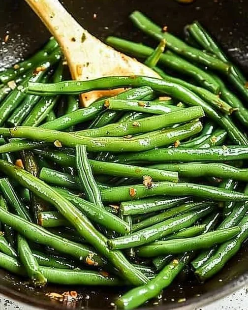 Sautéed green beans with garlic and seasoning in a skillet